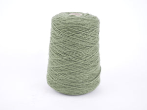 A cone of light sage green yarn wound on a white plastic core, photographed against a seamless white background.